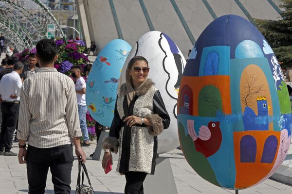 مردم در اطراف تخم های مرغ رنگارنگ در میدان آزادی تهران در 20 مارچ 2023 جمع می شوند تا جشن نوروز سال جدید فارس را جشن بگیرند. - اسپوتنیک افغانستان  