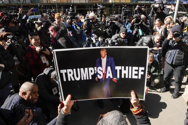 یک زن پوستری را به عنوان بخشی از تظاهرات در مقابل ساختمان دادگاه در آستانه کیفرخواست پیش بینی شده دونالد ترامپ، رئیس جمهور سابق آمریکا در روز دوشنبه، 20 مارچ 2023، در نیویورک به دست گرفته است. - اسپوتنیک افغانستان  