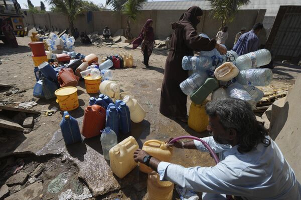 صف مردم برای آب آشامیدنی را از یک نقطه جمع آوری آب در یک منطقه فقیر نشین، در کراچی، پاکستان  - اسپوتنیک افغانستان  