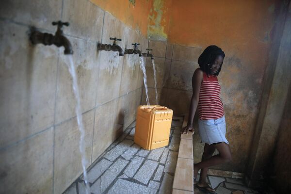 شخصی ظرفی را در یک ایستگاه پر کردن آب در پورتو پرنس، هائیتی پر می کند. - اسپوتنیک افغانستان  