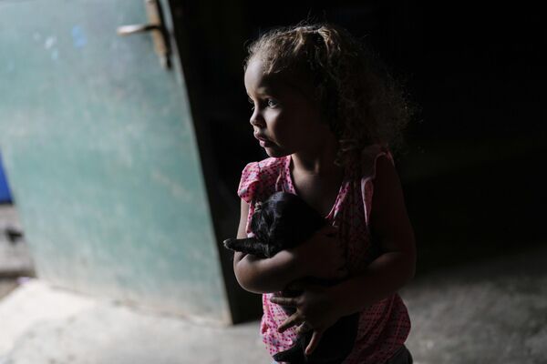 دختری در حالی که مادربزرگش ظرفی را با آب پمپاژ شده از چاهی در محله پتار کاراکاس، ونزوئلا پر می کند، توله سگی را حمل می کند.بزرگداشت روز جهانی آب در 22 مارچ مصادف با آغاز کنفرانس آب سال 2023 سازمان ملل متحد در نیویورک با هدف حل بحران آب و بهداشت است.دوشنبه 20 مارس 2023. - اسپوتنیک افغانستان  