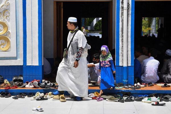 مردی و دخترش هنگام نماز در روز دوم ماه مبارک رمضان در شهر تاگویگ در منطقه مانیل در مقابل مسجدی قدم می زنند. - اسپوتنیک افغانستان  