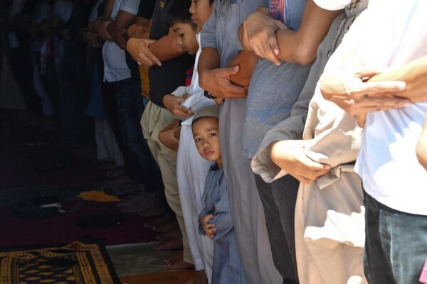 یک کودک مسلمان در دومین روز از ماه مبارک رمضان در مسجدی شهر تاگویگ در منطقه مانیل به همراه نزدیکانش نماز می خواند. - اسپوتنیک افغانستان  