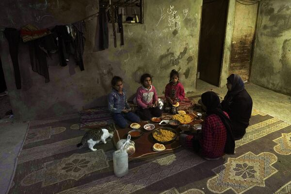 عبیر زروب، سمت راست، و فرزندانش روزه خود را در اولین روز از ماه مبارک رمضان در خانه خود که در نزدیکی محله ای فقیر نشین در منطقه خان یونس جنوب نوار غزه، قرار دارد افطار می کنند. - اسپوتنیک افغانستان  