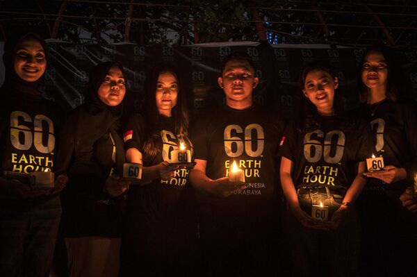 فعالان اندونزیایی در حین کمپاین زیست محیطی ساعت زمین در سورابایا در 25 مارچ 2023 در حالی که شمع در دست دارند عکس می گیرند. - اسپوتنیک افغانستان  