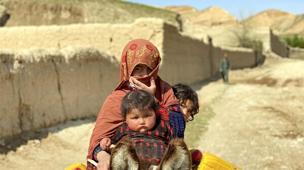 Афганская женщина с детьми едут верхом на осле по улице в районе Зари провинции Балх - اسپوتنیک افغانستان  