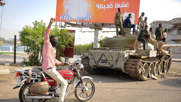 Мужчина поднимает руку в знак поддержки, проезжая мимо солдат суданской армии, занимающих позицию в городе Порт-Судан, Судан - اسپوتنیک افغانستان  