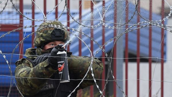 Польский военнослужащий распыляет спецсредство у проволочных заграждений на белорусско-польской границе - اسپوتنیک افغانستان  