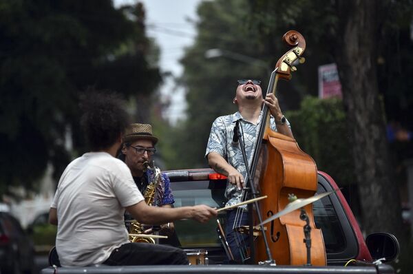 گروه Maroto Jazz Trio، متشکل از دیگو ماروتو با ساکسیفون، خورخه مولینا با کنترباس و ادی وگا نوازنده درام، در 29 آگیست 2020، در حین همه‌گیری ویروس کرونا، در بالای موتر در محله‌های مکزیکوسیتی اجرا می‌کنند. - اسپوتنیک افغانستان  