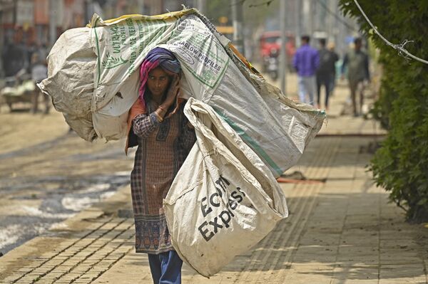 کارگری کیسه زباله را در امتداد خیابانی در سرینگر حمل می کند. - اسپوتنیک افغانستان  