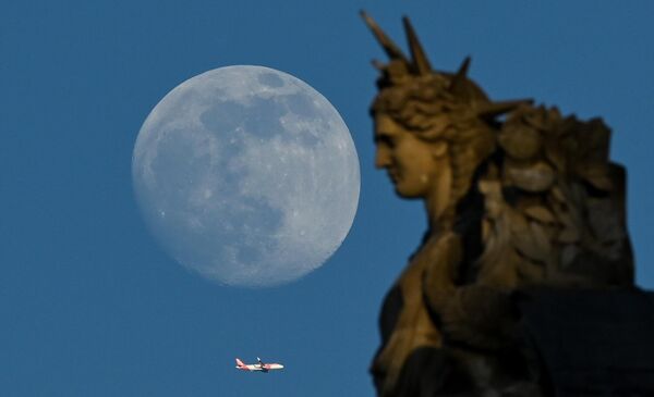 هنگام روئیت ماه کامل در پاریس، یک هواپیما از کنار مجسمه لوور در پرواز دیده می شود. - اسپوتنیک افغانستان  