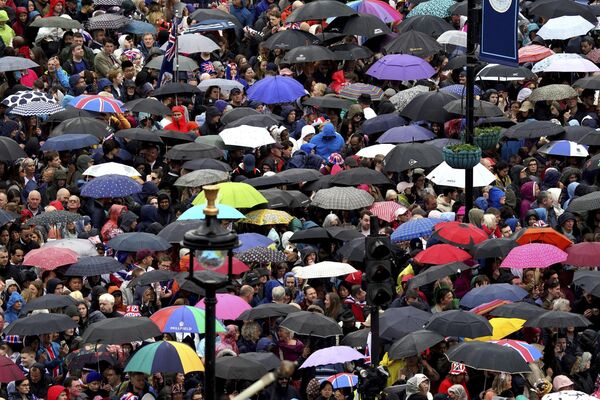 جمعیت نزدیک میدان ترافالگار پیش از مراسم تاجگذاری پادشاه چارلز سوم در کلیسای وست مینستر لندن، شنبه 6 می 2023، از باران پناه می برند. (گرت فولر) - اسپوتنیک افغانستان  