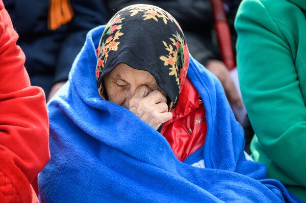 یک زن رسم و گذشت نظامی را به مناسبت هفتاد و هشتمین سالگرد پیروزی در جنگ بزرگ میهنی در میدان پیروزی در یوژنو-ساخالینسک تماشا می کند. - اسپوتنیک افغانستان  