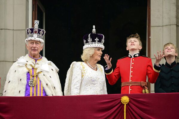 پادشاه بریتانیا، چارلز سوم، سمت چپ، و ملکه کامیلا، در کنار او، پس از مراسم تاجگذاری خود، در لندن، شنبه، 6 می 2023، از بالکن کاخ باکینگهام به بیرون نگاه می کنند.  - اسپوتنیک افغانستان  