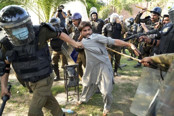 پلیس یکی از حامیان عمران خان نخست وزیر سابق پاکستان را که به همراه دیگران در اعتراض به دستگیری رهبر خود در لاهور پاکستان در روز چهارشنبه 10 می 2023 تظاهرات می کنند، بازداشت کرد. - اسپوتنیک افغانستان  