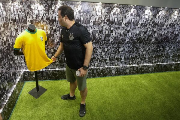 یکی از هواداران باشگاه فوتبال سانتوس یکی از پیراهن‌های فوتبال برزیل را که پله بزرگ فوتبال برزیل استفاده کرده بود، در هنگام بازدید از آرامگاهش که برای نخستین بار در گورستان یادبود نکروپولیس اکومنیکال در سانتوس، برزیل برای بازدید عموم افتتاح شد، لمس می‌کند. (عکس از اندری پینر خبرگزاری فرانسه) - اسپوتنیک افغانستان  