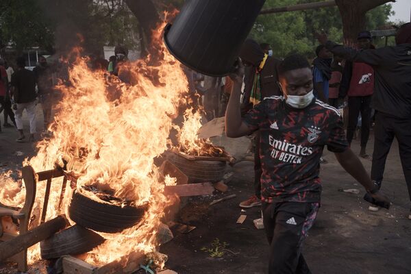 یک تظاهرکننده در روز دوشنبه، 29 می 2023 در حین تظاهرات در حمایت از عثمان سونکو، رهبر اصلی مخالفان در داکار، سنگال، از سدی عبور می‌کند که به آتش کشیده شد. این درگیری‌ها یک روز پس از آن رخ داد که پلیس &quot;کاروان آزادی&quot; سونکو را که از زادگاهش حرکت می‌کرد، متوقف کرد. از Ziguinchor، در جنوب و جایی که او شهردار است، به پایتخت، داکار، جایی که او را مجبور کردند به خانه‌ای که در شهر دارد، برود - اسپوتنیک افغانستان  