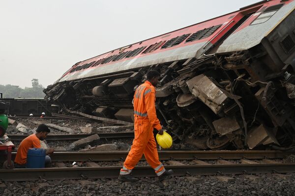 یک امدادگر در هنگام جستجوی بازماندگان در محل حادثه تصادف سه قطار در نزدیکی بالاسوره، در حدود 200 کیلومتری (125 مایلی) از مرکز ایالت بوبانسوار در ایالت شرقی اودیشا، در کنار یک قطار شکسته راه می‌رود. - اسپوتنیک افغانستان  