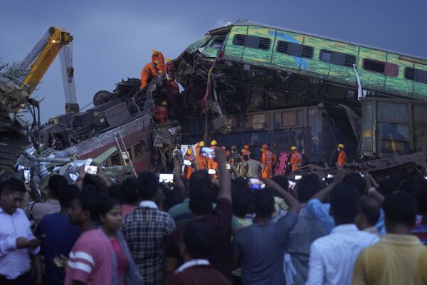 امدادگران برای بیرون آوردن جسد قربانی قطارهای مسافربری که در منطقه بالاسوره، در ایالت اوریسا در شرق هند، شنبه، 3 جون 2023 از ریل خارج شدند، تلاش می کنند. امدادگران در هند هیچ بازمانده دیگری در لاشه واژگون شده و درهم شکسته دو قطار پیدا نکردند. قطارهای مسافربری که از ریل خارج شدند و در یکی از مرگبارترین تصادفات ریلی کشور در چند دهه اخیر بیش از 280 نفر کشته و صدها نفر مجروح شدند. (عکس از /رفیق مقبول) - اسپوتنیک افغانستان  