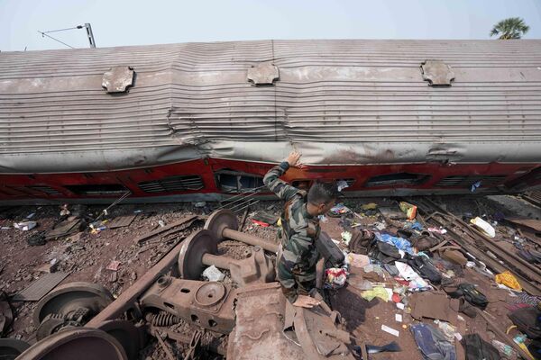 یک امدادگر شنبه، 3 جون 2023، از کنار آوار در محل قطارهای مسافربری خارج شده از ریل در منطقه بالاسوره، در ایالت شرقی اوریسا هند می گذرد. امدادگران در هند هیچ نجات‌یافته‌ای در لاشه واژگون شده و درهم شکسته دو قطار مسافربری پیدا نکرده‌اند. که از ریل خارج شد و در یکی از مرگبارترین تصادفات ریلی کشور در دهه های اخیر، بیش از 280 نفر کشته و صدها نفر زخمی شدند. عکس از /رفیق مقبول) - اسپوتنیک افغانستان  