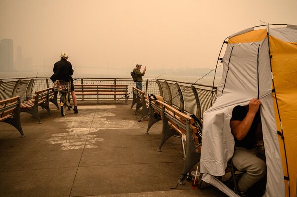 یک جوان از اسکای لاین منهتن عکس می گیرند. دود ناشی از آتش سوزی های جنگلی در کانادا باعث ایجاد شرایط تیرگی و آلودگی در شهر نیویورک شده است. چهارشنبه، 7 جون 2023 - اسپوتنیک افغانستان  