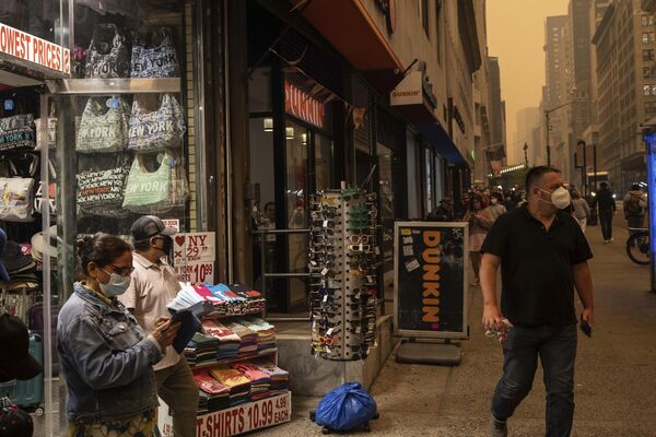 فردی در بیرون از فروشگاه صنایع دستی، در نیویورک ماسک می فروشد. 7 جون 2023 - اسپوتنیک افغانستان  
