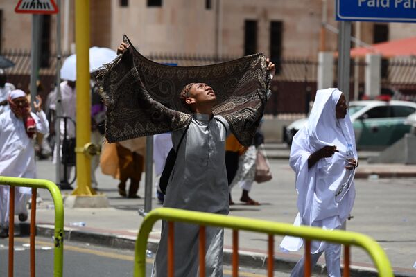 یک زائر مسلمان هنگام قدم زدن در شهر مقدس مکه برای محافظت از خود در برابر نور خورشید از سجاده نماز استفاده می کند.در 23 جون 2023(عکس از سجاد حسین / خبرگزاری فرانسه) - اسپوتنیک افغانستان  