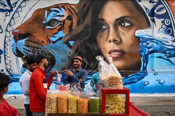 یک دستفروش غذای خیابانی را در نزدیکی یک نقاشی دیواری که به عنوان بخشی از همکاری خلاقانه بین هند و سفارت هلند ساخته شده است که نقاشی های دیواری چند شهر را برای بزرگداشت 75 سال رابطه دوجانبه بین دو کشور در دهلی نو آغاز می کنند، بساط کرده است.20 دسامبر 2022(عکس از سجاد حسین / خبرگزاری فرانسه) - اسپوتنیک افغانستان  