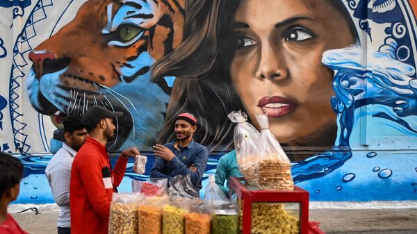 Торговец возле настенной росписи, созданной в рамках творческого сотрудничества между Индией и посольством Нидерландов, Нью-Дели, Индия - اسپوتنیک افغانستان  