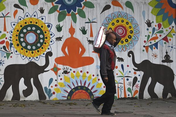 مردی از کنار یک نقاشی دیواری در دهلی نو عبور می کند.16 فبروری 2023(عکس از آرون سانکار / خبرگزاری فرانسه) - اسپوتنیک افغانستان  