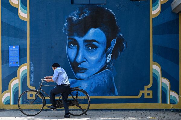 دوچرخه سواری از کنار یک نقاشی دیواری می گذرد که پرتره فلورانس ازکیل، بازیگر فقید بالیوود، معروف به نادیرا در دهلی نو را به تصویر می کشد.27 آپریل 2022(عکس از سجاد حسین / خبرگزاری فرانسه) - اسپوتنیک افغانستان  