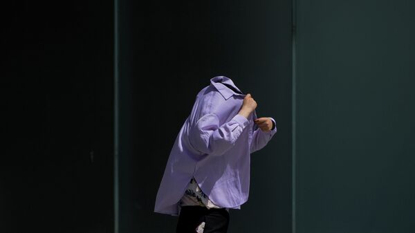 Женщина использует рубашку с длинным рукавом, чтобы защититься от солнца в Пекине, Китай - اسپوتنیک افغانستان  