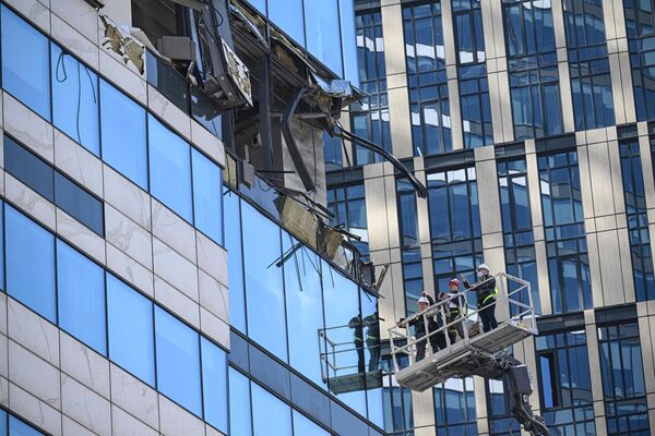 کارمندان تحقیقاتی آسیب وارد شده به ساختمان مرکز تجاری شهر مسکو را در نتیجه حمله پهپادهای اوکراینی بررسی می کنند. - اسپوتنیک افغانستان  