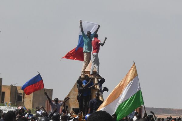 معترضان پرچم نیجر و روسیه را در حین تجمع در حمایت از حکومت نظامی نیجر در نیامی در 30 جولای 2023 به اهتزاز در می آورند.هزاران نفر از مردم روز یکشنبه در مقابل سفارت فرانسه در نیامی تظاهرات کردند، قبل از اینکه با گاز اشک آور متفرق شوند، در جریان تجمعی در حمایت از کودتاچیان نظامی که محمد بازوم، رئیس جمهور منتخب را در نیجر سرنگون کردند.قبل از پرتاب گاز اشک آور، چند سرباز جلوی سفارت ایستادند تا تظاهرکنندگان را آرام کنند. - اسپوتنیک افغانستان  