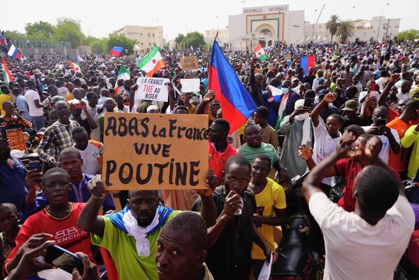 مردم نیجریه، یکشنبه 30 جولای 2023 در راهپیمایی به دعوت هواداران جنرال عبدالرحمن چیانی رهبر کودتا در نیامی نیجر شرکت می کنند.چند روز پس از اینکه سربازان شورشی رئیس جمهور منتخب نیجر را برکنار کردند، عدم اطمینان در مورد آینده این کشور افزایش یافته است و برخی دلایل حکومت نظامی برای به دست گرفتن کنترل را مطرح می کنند.روی این تابلو نوشته شده است: &quot;مرگ بر فرانسه، زنده باد پوتین&quot;. - اسپوتنیک افغانستان  
