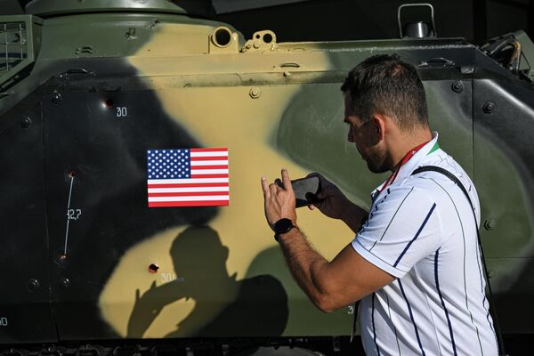مردی از سوراخ های گلوله در موتر زرهی امریکای تصرف شده در نمایشگاهی به عنوان بخشی از انجمن بین المللی فنی- نظامی ارتش-2023 در مرکز کنگره و نمایشگاه پاتریوت عکس می گیرد. - اسپوتنیک افغانستان  