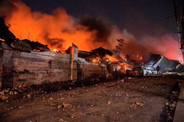 یک آتش نشان در حال خاموش کردن آتش پس از انفجار در یکی از شرکت های تجاری در سن کریستوبال، جمهوری دومینیکن. - اسپوتنیک افغانستان  