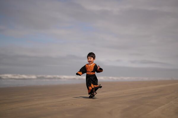 فرنیا حسنی، پناهجوی دو ساله افغان، در حال بازی کردن در ساحل پرایا گراند، ایالت سائوپائولو، برازیل. - اسپوتنیک افغانستان  