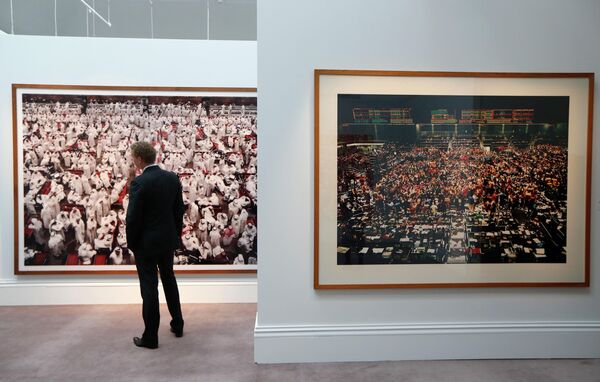 یک کارمند ساتبی با تصاویری عکس می گیرد که بورس اوراق بهادار کویت II، سمت چپ، و هیئت تجارت شیکاگو 1997، سمت راست، توسط آندریاس گورسکی را در خانه حراج در لندن، جمعه، 14 جون 2013 به نمایش گذاشته است.این تصاویر قرار است در حراج هنرهای معاصر با قیمت تخمینی 400000 تا 600000 پوند به حراج گذاشته شد. - اسپوتنیک افغانستان  