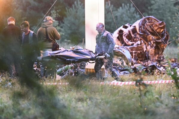 مردم یک کیسه جسد را از لاشه یک هواپیمای خصوصی سقوط کرده در نزدیکی روستای کوژنکینو در منطقه تور روسیه حمل می کنند. - اسپوتنیک افغانستان  