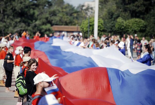 شرکت کنندگان در جشن های اختصاص داده شده به روز پرچم روسیه پرچم 100 متری روسیه را در میدان لنین در ماریوپول به اهتزاز درآوردند. - اسپوتنیک افغانستان  