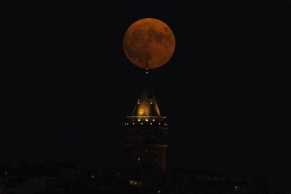 ماه کامل در پشت برج گالاتا در استانبول، ترکیه، چهارشنبه، 30 اگوست 2023 طلوع می کند. پرده کیهانی چهارشنبه شب با دومین ماه کامل ماه برخاست و به همین دلیل آبی در نظر گرفته می شود. به آن ابرماه لقب داده اند زیرا از حد معمول به زمین نزدیک تر است و به خصوص بزرگ و درخشان به نظر می رسد. (عکس آسوشیتدپرس/خلیل حمرا) - اسپوتنیک افغانستان  
