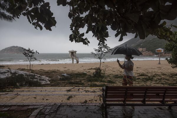 یک زن از ساحل پوشیده از شاخه های درخت پس از طوفان سائولا در دهکده ای ساحلی در هنگ کنگ فیلم می گیرد. - اسپوتنیک افغانستان  
