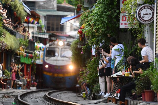 گردشگران از قطاری که از یک منطقه مسکونی قدیمی در مرکز هانوی، پایتخت ویتنام می گذرد، عکس می گیرند. 28 اگوست 2023 - اسپوتنیک افغانستان  