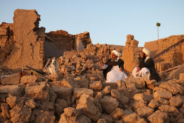 ساکنان افغانستان پس از زلزله در روستای سربلند زنده جان، ولسوالی هرات، در خانه آسیب دیده در 7 اکتوبر 2023 نشسته اند (عکس از محسن کریمی / خبرگزاری فرانسه) - اسپوتنیک افغانستان  