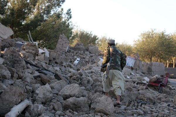 یک مرد از کنار خانه ویران شده پس از زلزله در ولسوالی زنده جان در ولایت هرات در غرب افغانستان. - اسپوتنیک افغانستان  