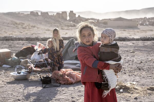 یک دختر افغان یک کودک را در میان ویرانی های پس از زلزله در ولسوالی زنده جان ولایت هرات حمل می کند. - اسپوتنیک افغانستان  
