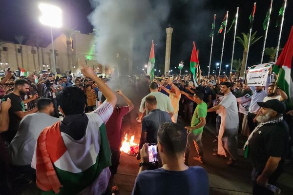 مردم پرچم ایالات متحده را در جریان تظاهرات در طرابلس پایتخت لیبیا در پایان روز 17 اکتبر 2023 در پشتیبانی از فلسطینیان پس از یورش به درمانگاه الاهلی در مرکز غزه که صدها کشته برجای گذاشت، آتش زدند.وزارت بهداشت حماس می‌گوید که حمله هوایی اسرائیل باعث  انفجار در درمانگاه  الاهلی شد که صدها نفر را  کشت، اما ارتش اسرائیل می‌گوید این یک موشک فلسطینی بود که بطور اشتباهی شلیک شده بود. - اسپوتنیک افغانستان  