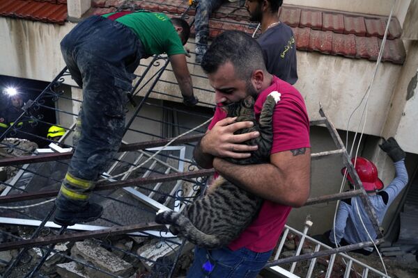یک مرد پشکی را در آغوش می گیرد که زنده از زیر ویرانه های یک ساختمان که بخشی از آن فرو ریخته است، بیرون کشیده شده است. این حادثه در شهر منصوریه لبنان در جنوب شرقی بیروت رخ داده است. - اسپوتنیک افغانستان  