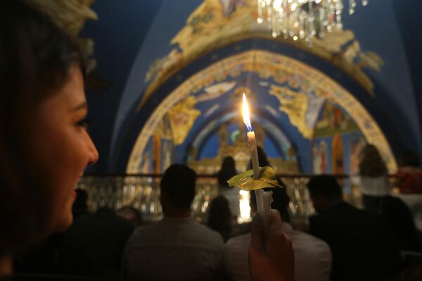 یک مسیحی ارتدوکس یونانی فلسطینی شمعی روشن از &quot;آتش مقدس&quot; در کلیسای سنت پورفیریوس در شهر غزه در طول جشن های عید در دست دارد. - اسپوتنیک افغانستان  